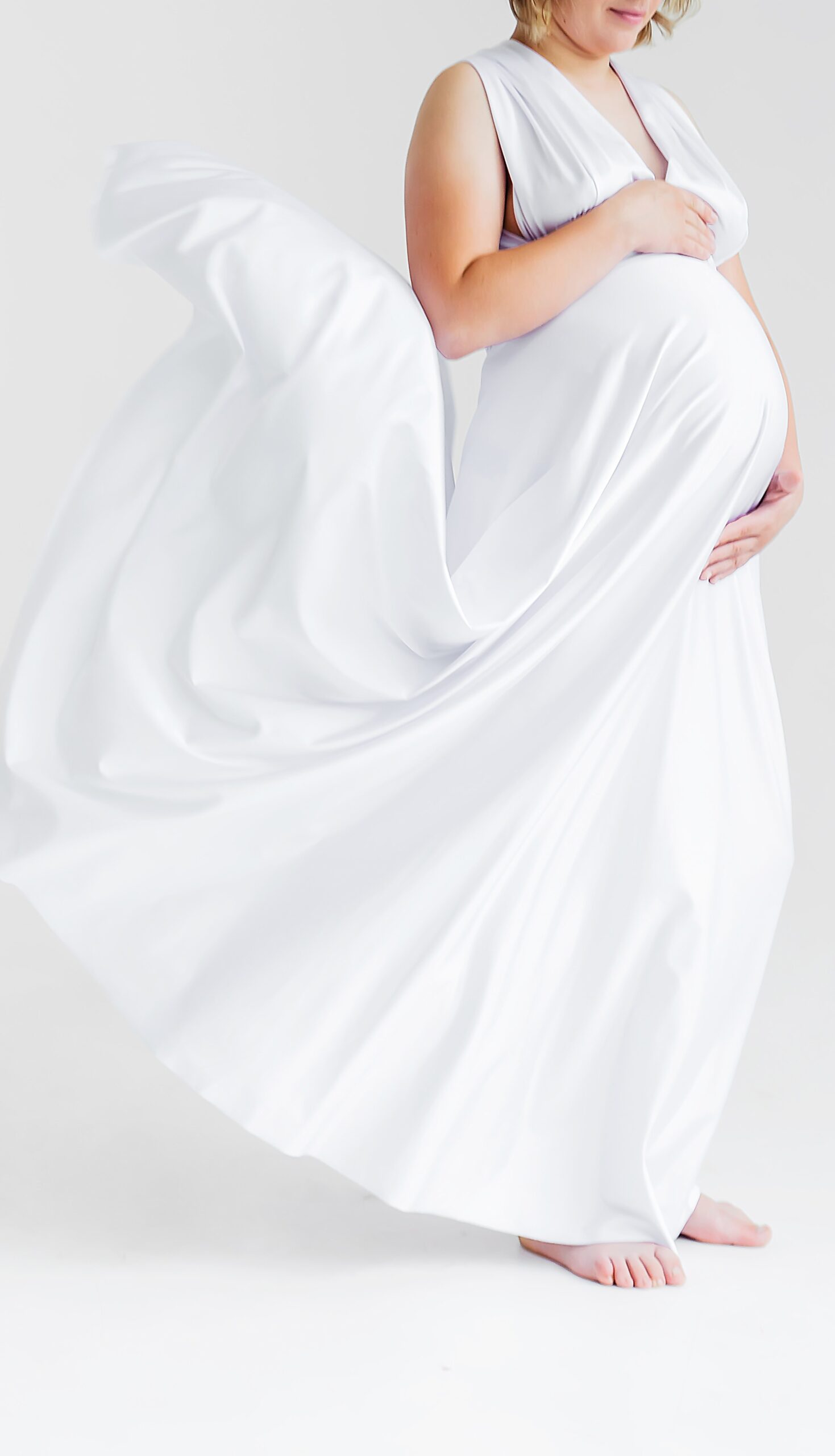 Experience-the-Road-to-Fertility-Difference-Fisher-Island-1 Maternity portrait of a pregnant woman in a flowing white dress, embracing her baby bump.