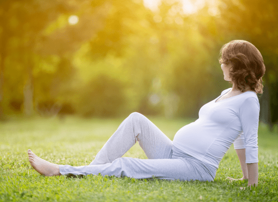 happy pregnant woman late pregnancy stage sitting grass lawn