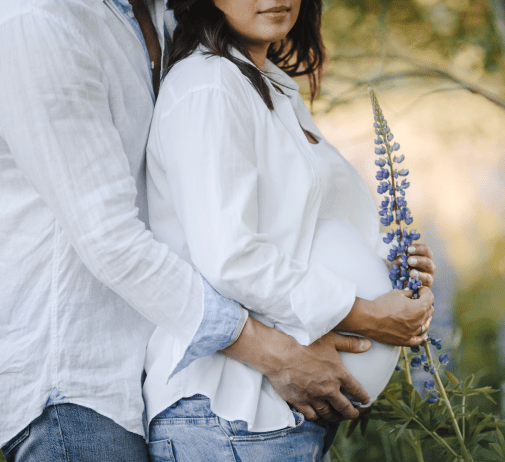 husband hugs back his pregnant wife lupins field close up